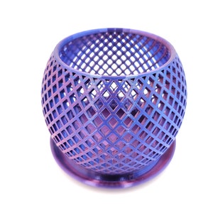 May include: A purple metal planter with a geometric diamond pattern. The planter has a round base and a wide opening.