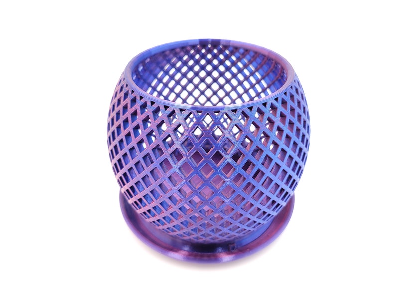 May include: A purple metal planter with a geometric diamond pattern. The planter has a round base and a wide opening.