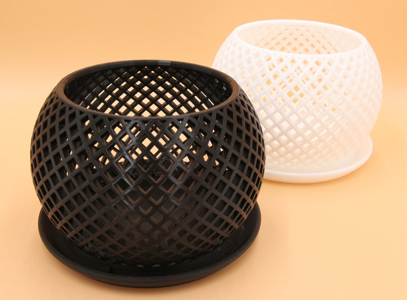 May include: Two round, geometric planters with a diamond pattern. One planter is black and the other is white. Both planters have a matching saucer.