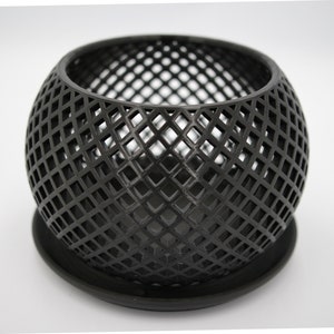 May include: Black metal planter with a geometric diamond pattern. The planter has a round shape and a matching base.