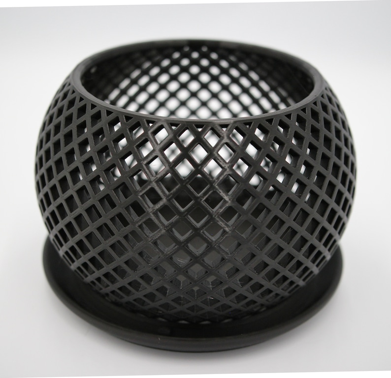 May include: Black metal planter with a geometric diamond pattern. The planter has a round shape and a matching base.