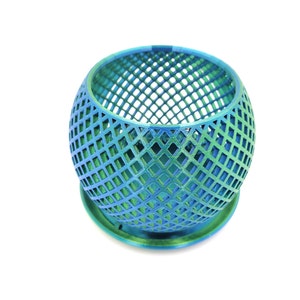 May include: A teal and green metallic planter with a geometric grid pattern. The planter has a round base and a wide opening.