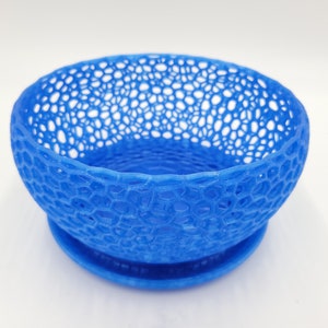May include: A blue, 3D printed bowl with a lacy, openwork design. The bowl has a matching base.
