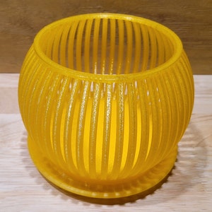 May include: A yellow, cylindrical planter with a woven design. The planter has a smooth, shiny finish and a round base.
