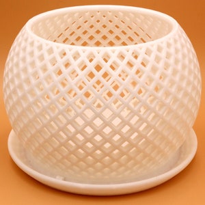May include: White ceramic planter with a geometric, diamond-shaped lattice design. The planter has a separate saucer.