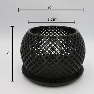 May include: Black metal candle holder with a geometric design. The holder is 7 inches tall and has a diameter of 6.75 inches. It comes with a matching base.