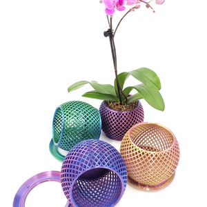 May include: Four iridescent, geometric, spherical planters with a pink orchid plant in one of the planters. The planters are made of a mesh-like material and have a metallic finish.