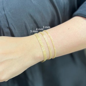 K&ouml;nnte beinhalten: Drei goldene Kettenarmb&auml;nder an einem Handgelenk, beschriftet mit 3 mm, 4 mm und 5 mm.
