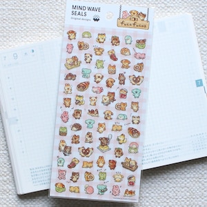 Peut inclure: Une planche d'autocollants Mind Wave Seals avec divers animaux de dessins animés et aliments. Les autocollants sont sur un fond à carreaux roses et blancs. Les autocollants sont sur un carnet ouvert avec du papier quadrillé.