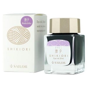 A square glass bottle of Shikiori dye ink, 20ml, with a gold cap, next to a white box. The box and bottle have purple and gold labels with Japanese text and the Sailor logo. The ink is for fountain pens.