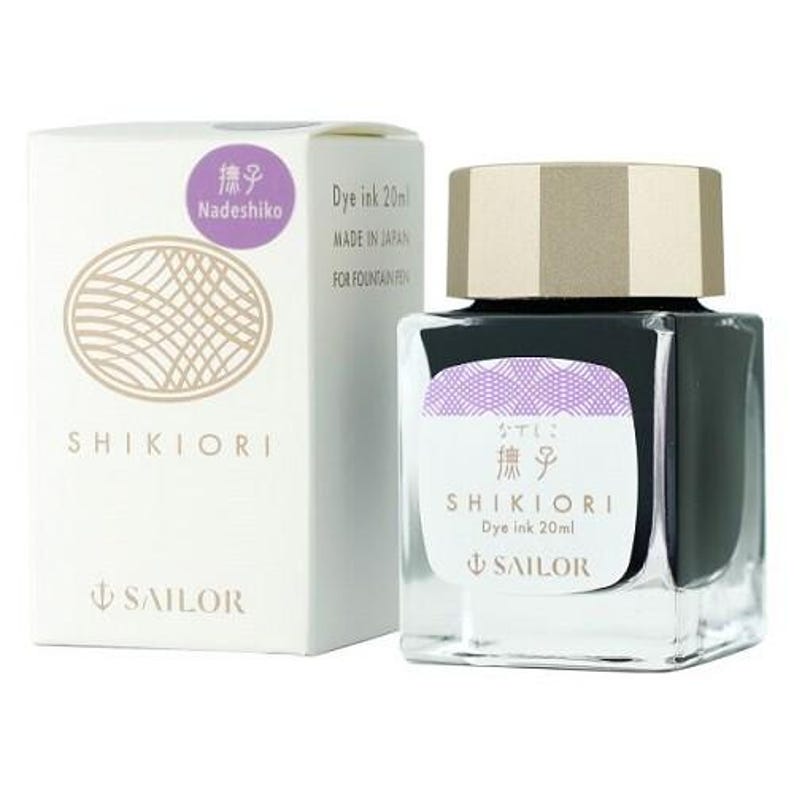 A square glass bottle of Shikiori dye ink, 20ml, with a gold cap, next to a white box. The box and bottle have purple and gold labels with Japanese text and the Sailor logo. The ink is for fountain pens.