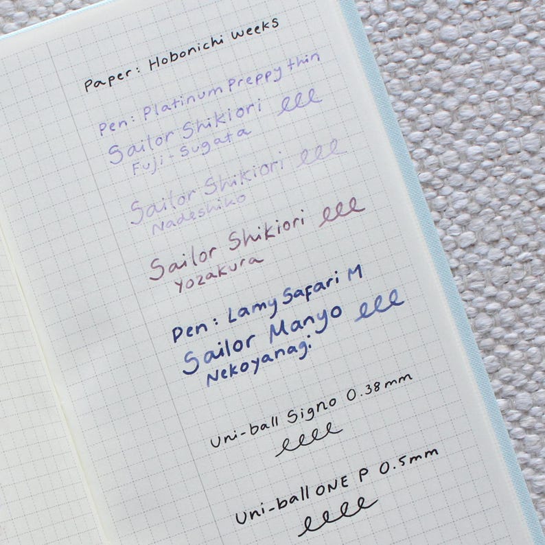 Open notebook page with grid lines, featuring handwritten pen tests in various colors. The text includes "Paper: Hobonichi weeks" and pen brands like "Sailor Shikiori" and "Uni-ball Signo 0.38mm".