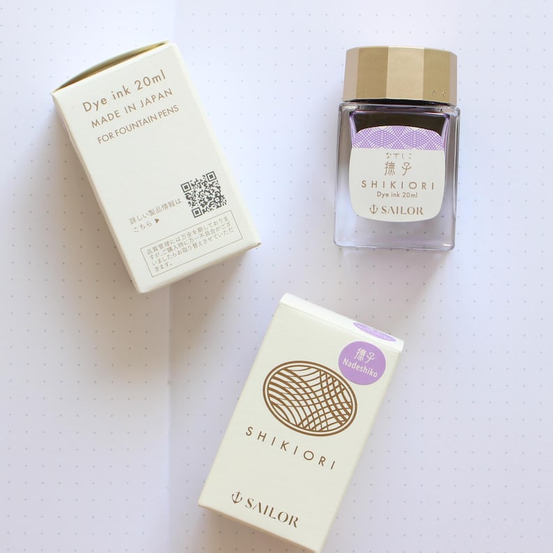 A clear glass bottle of Shikiori dye ink, 20ml, with a gold cap and a white label with Japanese text. Matching boxes with the text "SHIKIORI" and "SAILOR" are next to the bottle.