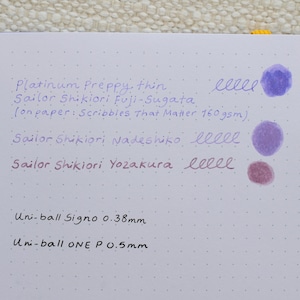 A white sheet of paper with ink tests. The text includes "Platinum Preppy, thin", "Sailor Shikiori Fuji-Sugata", "Sailor Shikiori Nadeshiko", and "Sailor Shikiori Yozakura". There are ink blotches and writing samples in purple and red.