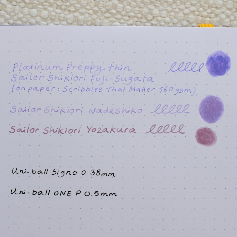 A white sheet of paper with ink tests. The text includes "Platinum Preppy, thin", "Sailor Shikiori Fuji-Sugata", "Sailor Shikiori Nadeshiko", and "Sailor Shikiori Yozakura". There are ink blotches and writing samples in purple and red.