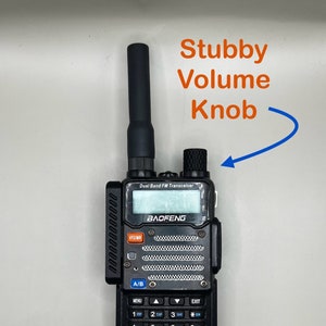 May include: A black handheld two-way radio with a black antenna, a small volume knob, and a keypad with numbers and symbols. The radio has the text "BAOFENG" and "UV-5RV2+" printed on it.