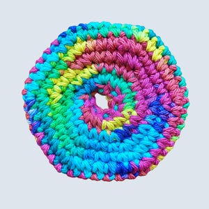 Puede incluir: Un posavasos de ganchillo hecho a mano y colorido con un agujero central. El posavasos presenta un diseño en espiral con tonos vibrantes de azul, verde, amarillo, rosa y morado. La forma hexagonal añade un toque único a este artículo decorativo.