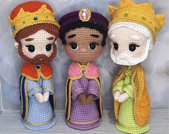 Puede incluir: Tres figuras de crochet de los Reyes Magos, cada una con una corona y una túnica. Las figuras están de pie sobre una superficie de madera. El texto "Reyes Magos" y "by Nuna (Andrea Sierra)" es visible en la parte inferior de la imagen.