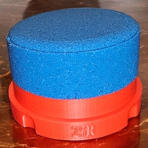 May include: A blue and red cylindrical object with a textured surface and the number "25R" printed on the bottom.