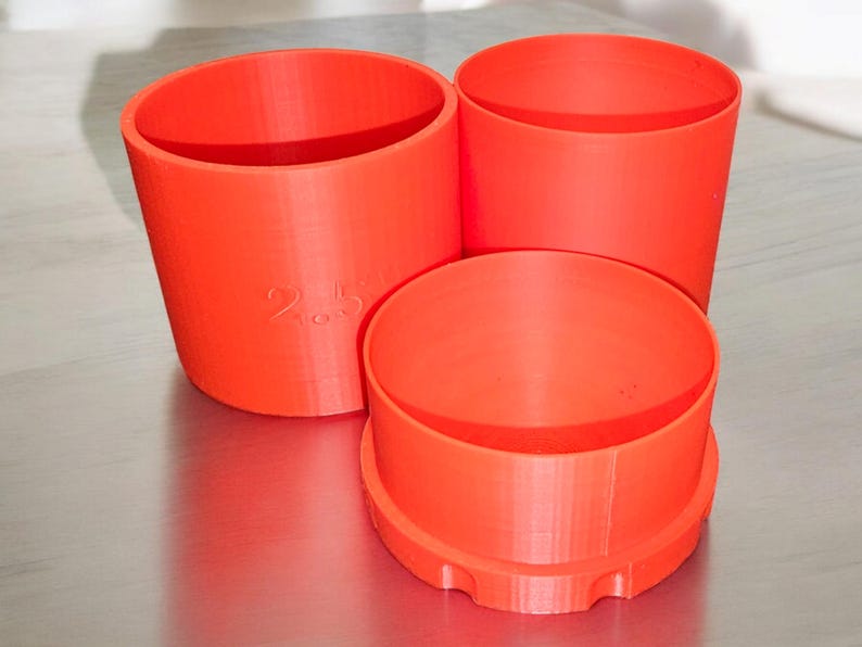 May include: Three orange plastic containers of different sizes. The largest container has the number "2.5" printed on the side.