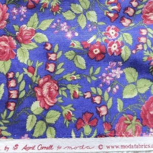 Puede incluir: Una tela azul con un patrón floral repetitivo de rosas rojas y hojas verdes. El borde blanco muestra el texto: Devon Rose by April Cornell for moda © www.modafabrics.com Pattern #35070. El diseño incluye pequeñas flores de color rosa.