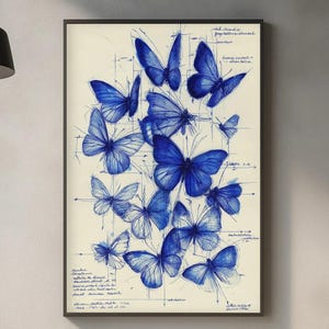 Peut inclure: Impression encadrée représentant des illustrations de papillons bleus. L'œuvre présente de nombreux papillons de différentes tailles et poses, dessinés en détail sur un fond crème. Des lignes de grille et des notes manuscrites sont également visibles.