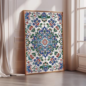May include: A rectangular framed wall art piece featuring a white background with a repeating symmetrical floral pattern in shades of deep blue, forest green, and terracotta red. The artwork is encased in a thin, light-toned wooden frame.