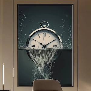 May include: A framed artwork featuring a silver pocket watch submerged in water. The watch face is white with black Roman numerals and hands. Water splashes around the watch, creating a dynamic visual effect. The background is a dark teal.