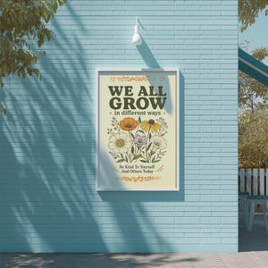 a poster with a floral design and the text "WE ALL GROW in different ways" displayed on a blue brick wall.