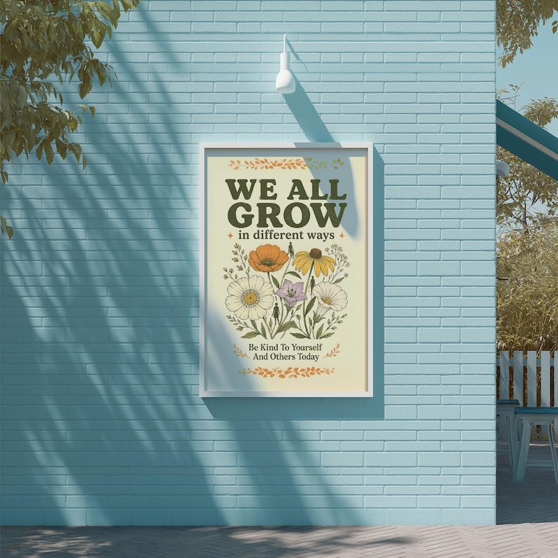 a poster with a floral design and the text "WE ALL GROW in different ways" displayed on a blue brick wall.