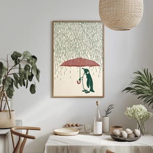a cozy dining area with a framed illustration of a penguin holding an umbrella, surrounded by greenery and a table set with various items.