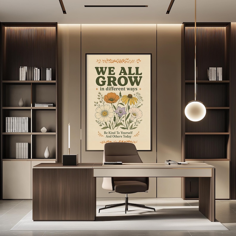 a modern office space with a large framed poster on the wall that reads "WE ALL GROW in different ways" and "Be kind to yourself and others today". The office has a wooden desk, a chair, and a bookshelf filled with books. The overall design and decor create a professional and comfortable atmosphere.