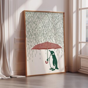A framed illustration depicting a penguin holding an umbrella, with rain falling around it.