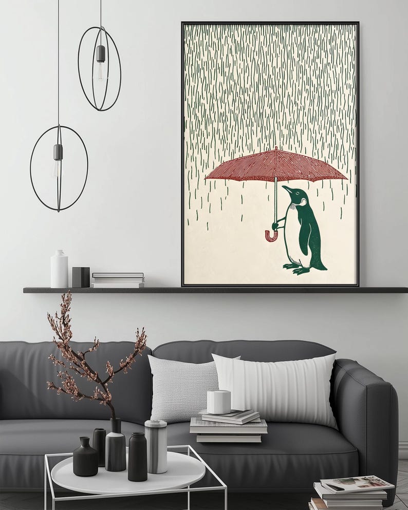 a cozy living room with a gray couch, a coffee table, and a framed artwork depicting a penguin holding an umbrella. The artwork is hanging on the wall above the couch, creating a warm and inviting atmosphere.