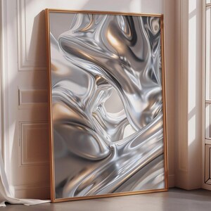 May include: Abstract metallic art print in a gold frame. The artwork features a flowing, liquid-like design in shades of silver and gold, creating a sense of movement and depth. The framed art leans against a white wall.