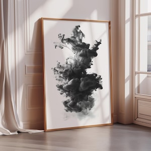 May include: A framed art print featuring a black ink cloud design against a white background. The artwork is in a gold frame and leans against a white wall. The abstract design creates a dramatic visual effect.
