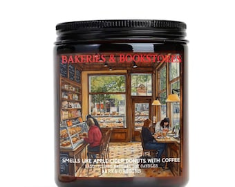 May include: A brown glass candle jar with a black lid. The label features a painting of a bakery and bookstore interior with people sitting at tables. The text on the label reads "Bakeries & Bookstores", "Smells like apple cider donuts with coffee", "Hand-poured natural soy candles", and "Aarka Origins".