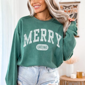 Op de afbeelding: Een groen sweatshirt met de tekst "Merry Christmas" in witte letters. Het sweatshirt heeft een ontspannen pasvorm en een ronde hals.