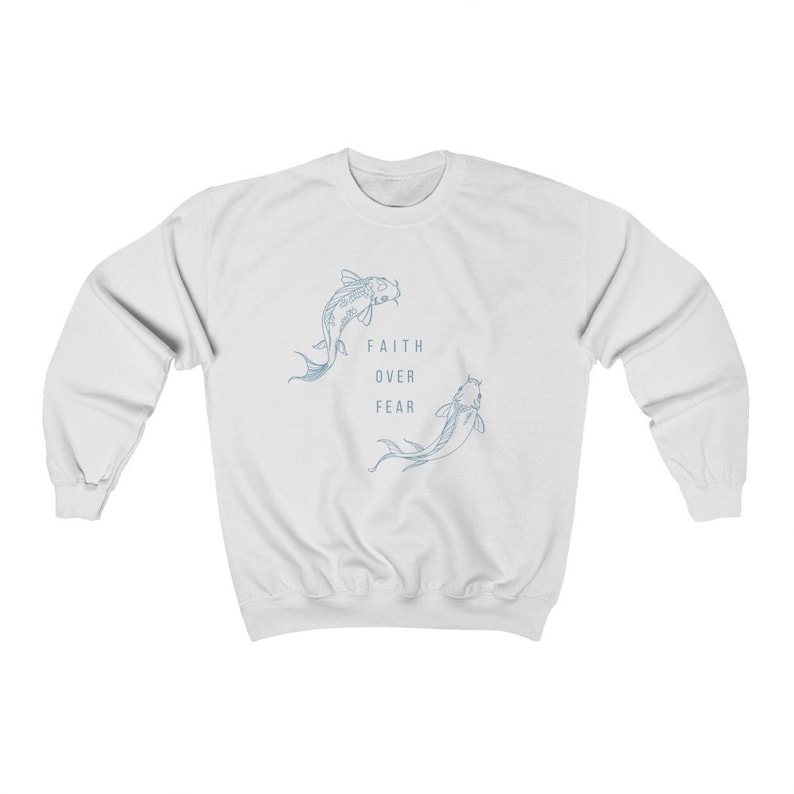 Puede incluir: Sudadera blanca con un contorno azul de dos peces nadando en c&iacute;rculo. El texto "FAITH OVER FEAR" est&aacute; impreso en el centro del c&iacute;rculo.