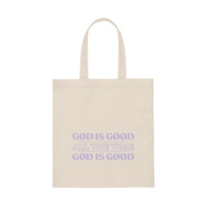 May include: A beige tote bag with a purple design that says "God is good all the time God is good".