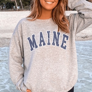May include: A gray sweatshirt with a blue vintage-style graphic that says "MAINE" on the front.