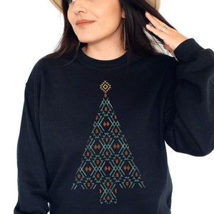 Könnte beinhalten: Ein schwarzes Sweatshirt mit einem geometrischen Weihnachtsbaum-Design in Grün-, Braun- und Orangetönen.