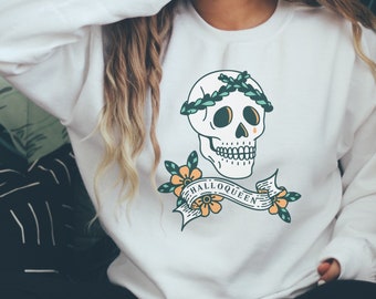 May include: White sweatshirt with a graphic of a skull wearing a leafy crown and a banner that reads "Halloqueen".