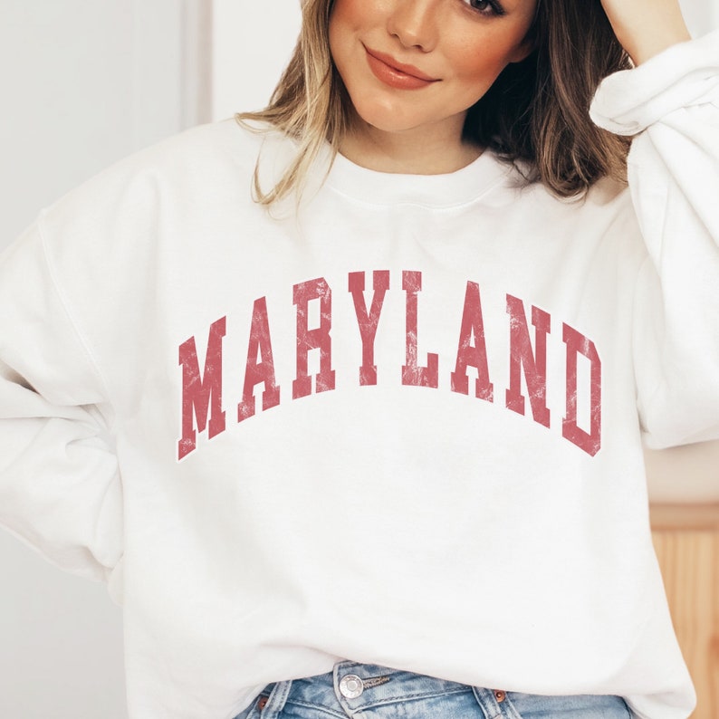 May include: White sweatshirt with a red vintage-style graphic that says "MARYLAND".