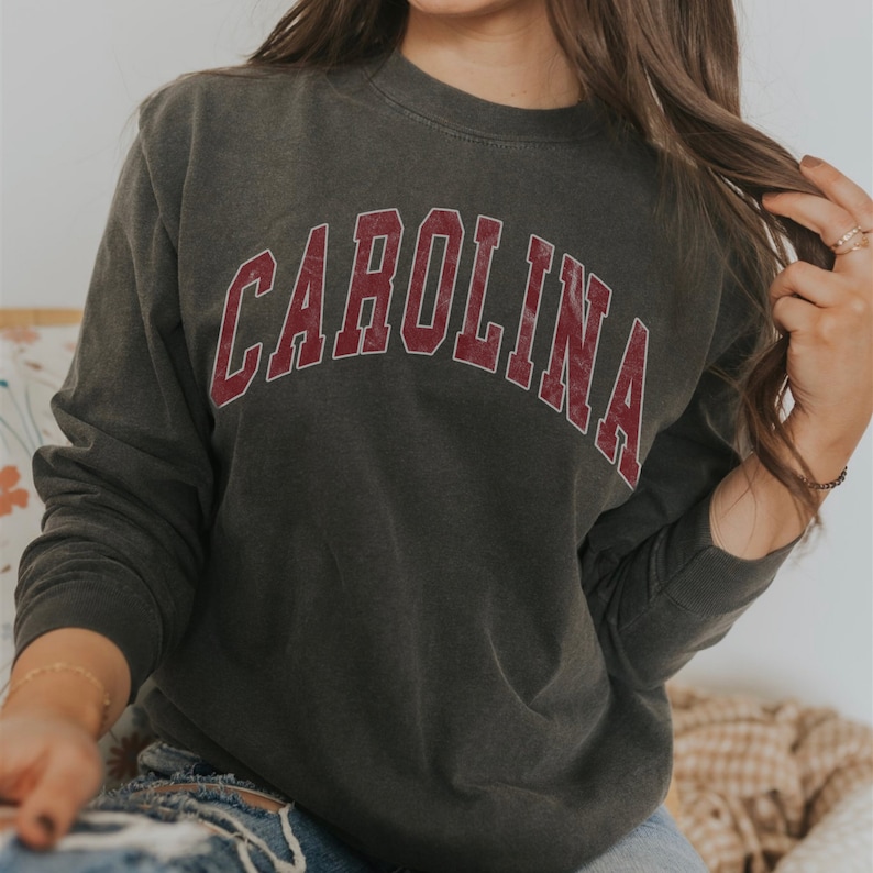 May include: A dark gray sweatshirt with a red vintage-style "CAROLINA" graphic.
