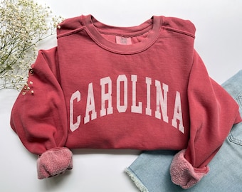 May include: A red sweatshirt with the word "CAROLINA" printed in white on the front.