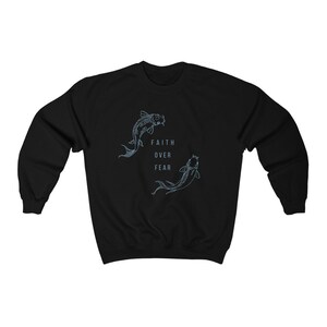 Puede incluir: Sudadera negra con un gr&aacute;fico de dos peces koi nadando en c&iacute;rculo con el texto "Faith Over Fear" en el centro.
