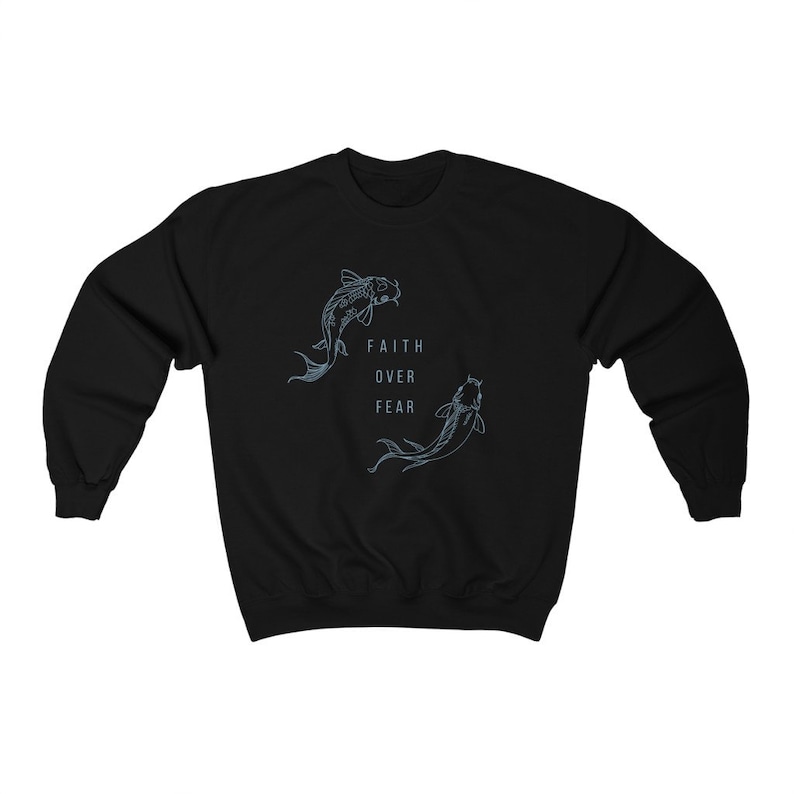 Puede incluir: Sudadera negra con un gr&aacute;fico de dos peces koi nadando en c&iacute;rculo con el texto "Faith Over Fear" en el centro.