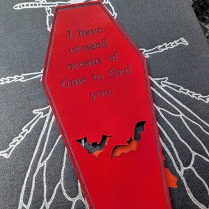 May include: Red coffin-shaped bookmark with a black bat cutout and the text "I have crossed oceans of time to find you."