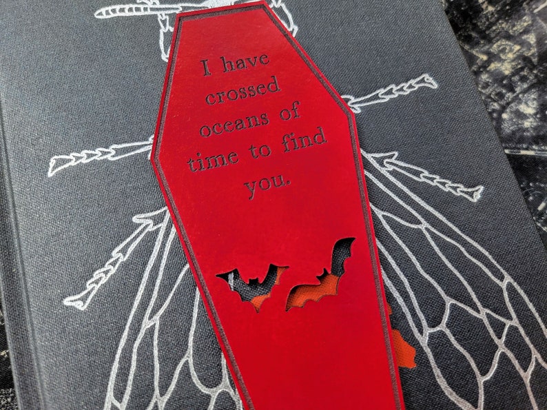 May include: Red coffin-shaped bookmark with a black bat cutout and the text "I have crossed oceans of time to find you."